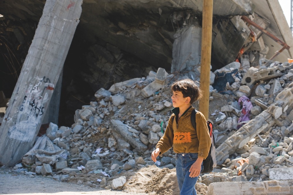 A child in Gaza leaves school following Israeli strikes in 2009 A child in Gaza leaves school surrounded by rubble, following Israeli strikes in 2009