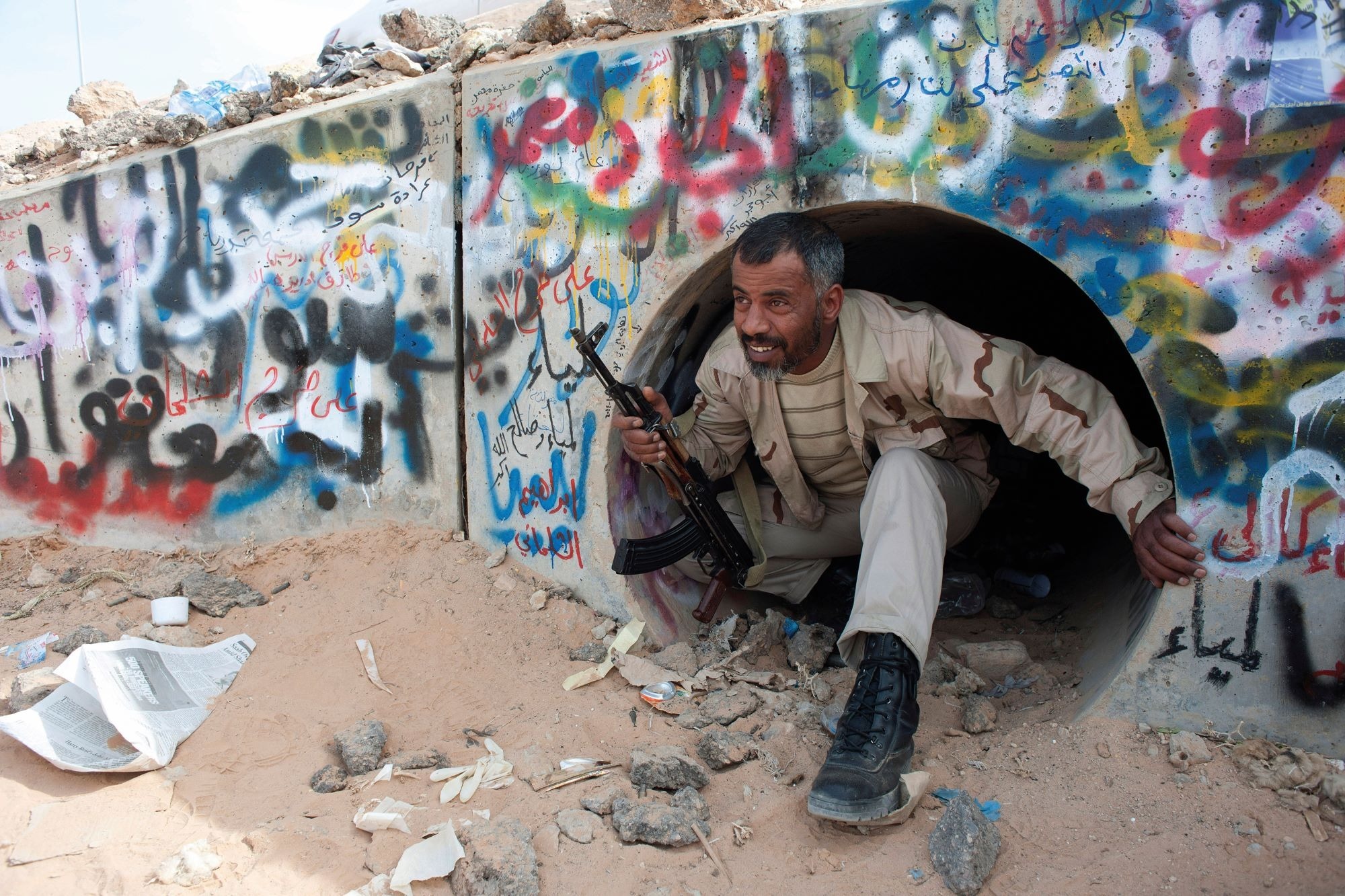 A Libyan rebel in the town of Sirt demonstrates how they found Gaddafi hiding out in this tunnel. Credit: Alamy A Libyan rebel crouches down inside a graffiti-covered concrete tunnel as he demonstrates how they found Gaddafi hiding inside
