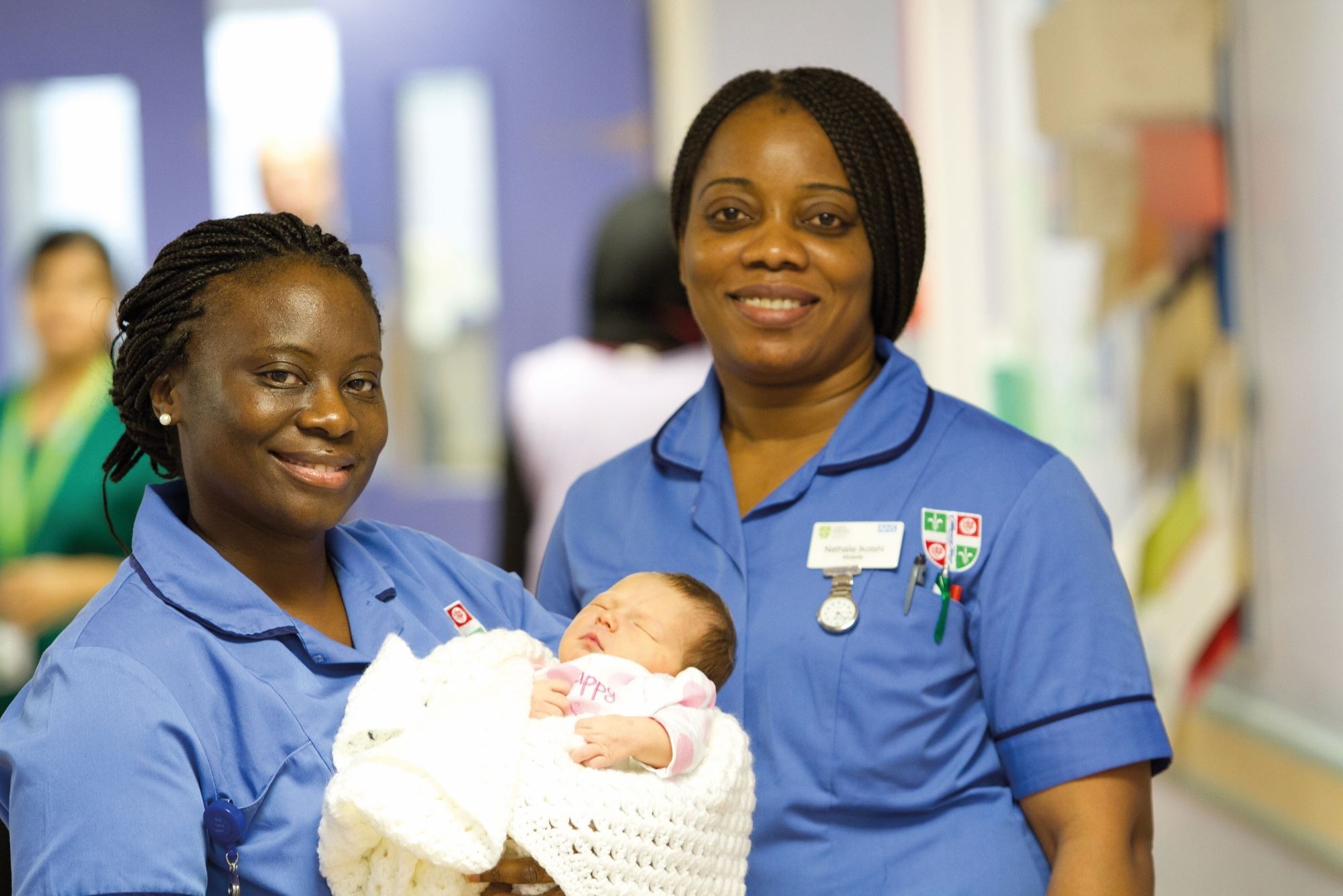 Many people working in the NHS are raised in families that value responsibility, says one expert Two smiling nurses hold a baby
