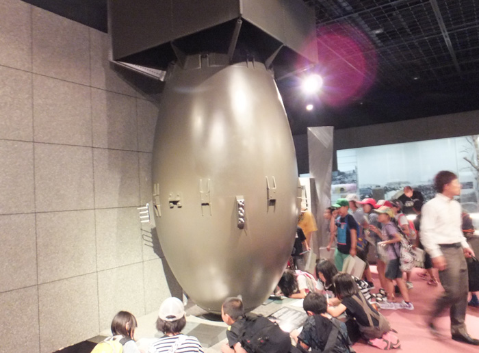 Children sit under the model of Kids with atomic bomb