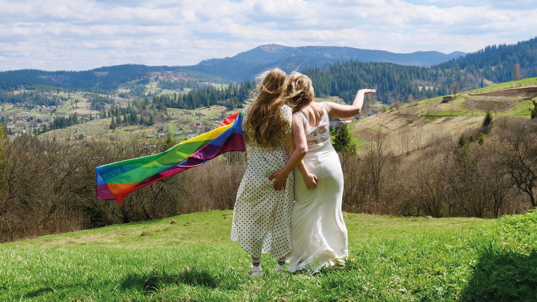Alamy Stock Photo A pair of brides waving the rainbow flag on their wedding day