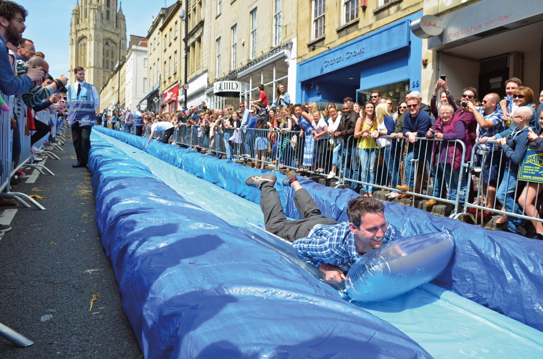 Adults play on water slide set up in Bristol, May 2014. Credit: Alamy Adults play on a waterslide