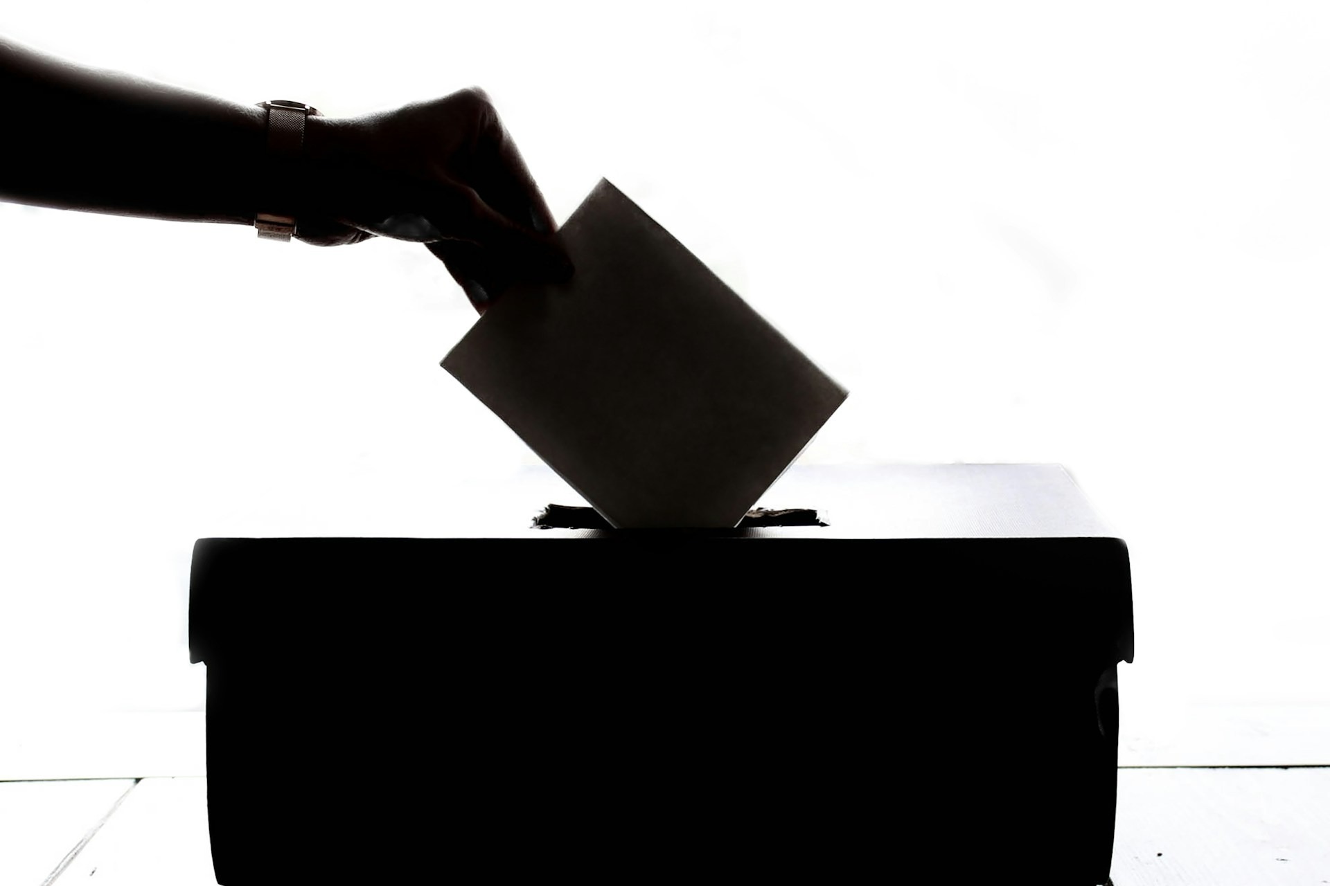 A hand places a card into a ballot box