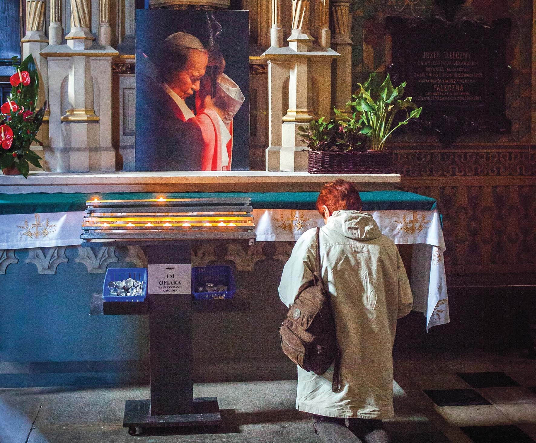 A woman praying in front of a portrait of John Paul II in Krakow, Poland A woman praying in front of a portrait of John Paul II in Krakow, Poland