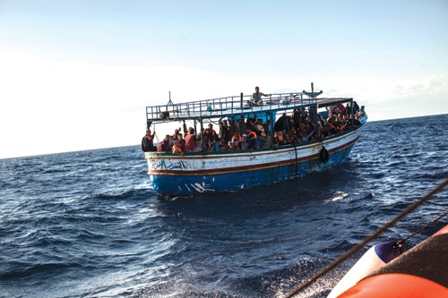 A fishing boat containing 177 refugees from the war in Syria approaches an Italian coastguard vessel, October 2013 Migrant boat